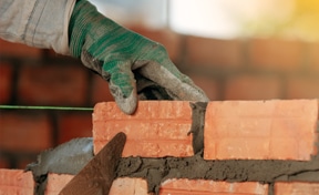 Mason fitting a brick.